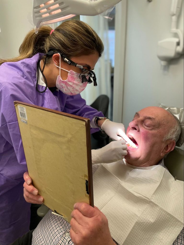 Dental hygienist flossing a patient in the dental office.